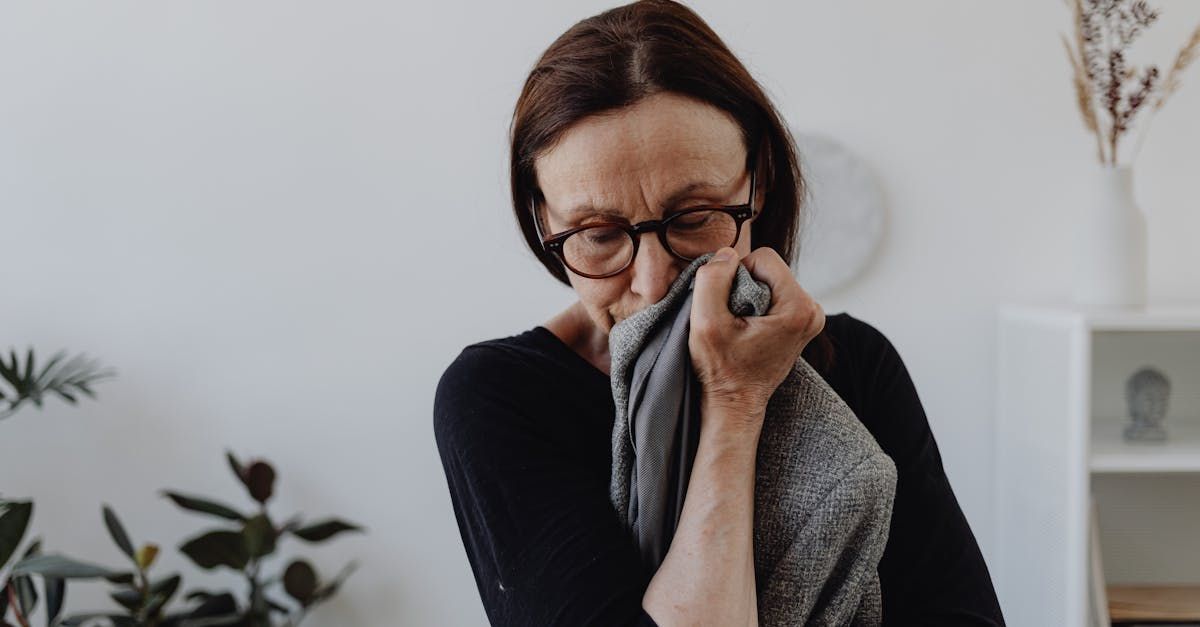Woman with glasses holding a cloth to her face in grief