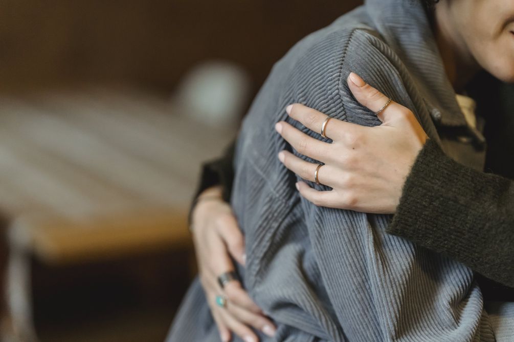 A hand resting comfortingly on another person’s shoulder