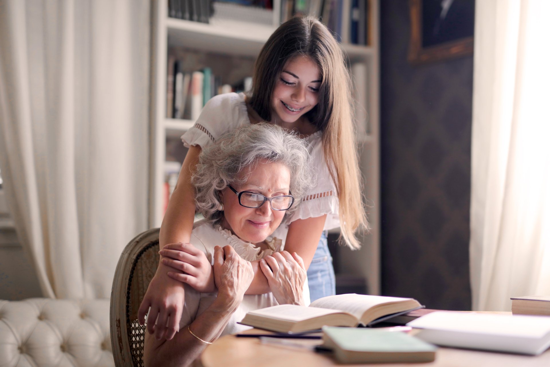 Young woman helping an elderly woman with a book